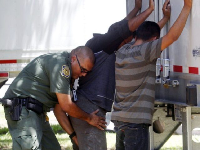In this Sunday, Aug. 13, 2017, photo, a Border Patrol officer pats down several of the men that were found with a group of immigrants in a tractor-trailer in Edinburg, Texas. Police in Texas acting on a tip found the immigrants locked inside a tractor-trailer parked at a gas station about 20 miles (30 kilometers) from the border with Mexico, less than a month after 10 people died in the back of a hot truck with little ventilation in San Antonio. (Delcia Lopez/The Monitor via AP)