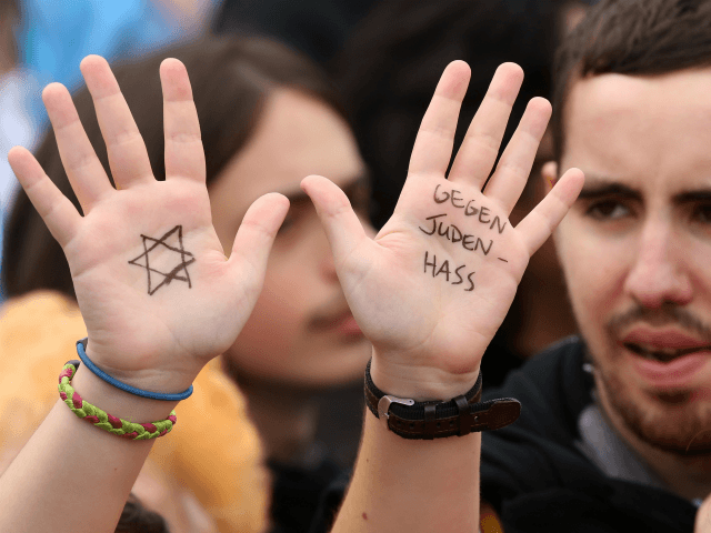 Um visitante com uma estrela de Davi e as palavras "Contra o ódio contra judeus", escrito em suas mãos, assiste a uma manifestação contra o anti-semitismo em 14 de setembro de 2014 em Berlim, na Alemanha.  Com o slogan 'Stand Up!  Nunca mais o ódio contra os judeus (o "Steh auf! Nie wieder Judenhass"), o Conselho Central dos Judeus na Alemanha (Zentralrat der Juden) organizou a manifestação após incidentes antisemitas no país que ocorreram na sequência do conflito em Gaza neste verão, em que mais de 2.000 palestinos foram mortos pelo governo israelense, a maioria dos quais civis, de acordo com autoridades palestinas.  (Foto de Adam Berry / Getty Images)