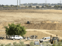 Hamas security forces secure the area while Palestinian bulldozers, at foreground, and Israeli backhoes, at midground, search the destroyed tunnel for the missing of five Islamic Jihad militants near the Israeli border east of Khan Younis, Gaza Strip, Friday, Nov. 3, 2017. The Islamic Jihad, says five of its members who have been missing since Israel demolished a militant tunnel dug from Gaza into Israel this week have died, the group said Friday that the militants' remains are on the Israeli side of the tunnel after searching for them on the Palestinian side. (AP Photo/Adel Hana)