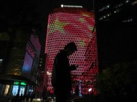 TOPSHOT - A man looks at his phone near a giant image of the Chinese national flag on the side of a building in Beijing, during the ongoing 19th Communist Party Congress on October 23, 2017. / AFP PHOTO / GREG BAKER (Photo credit should read GREG BAKER/AFP/Getty Images)