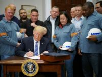 Donald Trump signs tariffs on steel and aluminum imports next to industry workers at the White House on March 8, 2018