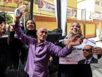 Egyptians dance and celebrate with an electoral poster of incumbent President Abdel Fattah al-Sisi outside a polling station in central Cairo