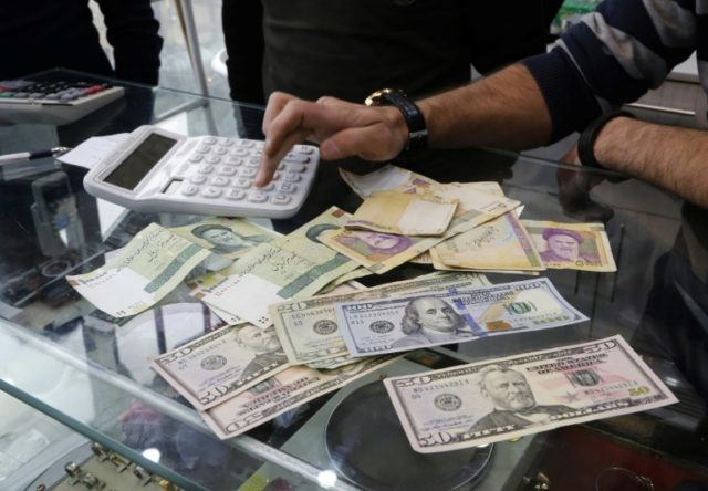 Iranians trade money at an currency exchange office in a shopping centre in Tehran on December 28, 2016