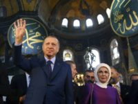 Turkey's President Recep Tayyip Erdogan, centre, accompanied by his wife Emine, right, waves to supporters as he walks in the Byzantine-era Hagia Sophia an UNESCO world heritage site and one of Istanbul's main tourist attractions, in the historic Sultanahmet district of Istanbul, Saturday, March 31, 2018. Turkey's president has recited an Islamic prayer in the Hagia Sophia, an Istanbul landmark that has become a symbol of interfaith and diplomatic tensions. Erdogan recited the Quran's first verse to the "souls of all, especially Istanbul's conqueror." The Hagia Sophia was built as an Orthodox Christian church, converted into a mosque in 1453 and made into a museum in 1935. Erdogan's Islamic-leaning government has discussed converting the structure back into a mosque. (Kayhan Ozer/Pool Photo via AP)