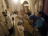 Archbishop Pierbattista Pizzaballa, center, apostolic administrator of the Latin Patriarch of Jerusalem, holds a statue of Baby Jesus in Saint Catherine's Church at the end of the Christmas Midnight Mass and walks in procession to the 'Grotto', where Christians believe the Virgin Mary gave birth to Jesus Christ, in the adjacent Church of the Nativity in Bethlehem, West Bank Sunday, Dec. 25, 2016. (Musa Al Shaer/Pool Photo via AP)