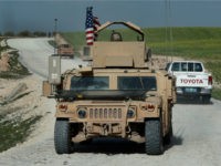 In this picture taken on Thursday, March 29, 2018, U.S. troop's humvee passes vehicles of fighters from the U.S-backed Syrian Manbij Military Council on a road leading to the tense front line with Turkish-backed fighters, at Halawanji village, north of Manbij town, Syria. The front line has grown more tense in recent days as Turkey threatens to advance on the town to clear it of the U.S-backed fighters. U.S troops have increased their patrols in the area, local commanders say, to prevent an outbreak of fighting and to prevent Turkey from advancing on Manbij. (AP Photo/Hussein Malla)