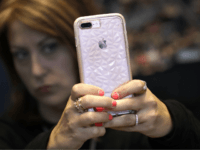 A customer uses her Apple iPhone X during an Apple event at their main store Tuesday, March 27, 2018, in Chicago. (AP Photo/Charles Rex Arbogast)