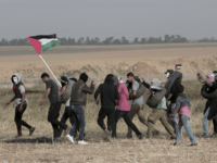 Palestinian masked protesters carrying tires walk toward the border fence during clashes with Israeli troops along Gaza's border with Israel, east of Khan Younis, Gaza Strip, Thursday, April 5, 2018. An Israeli airstrike in northern Gaza early on Thursday killed a Palestinian, while a second man died from wounds sustained in last week's mass protest. The fatalities bring to 21 the number of people killed in confrontations in the volatile area over the past week with a new round of protests along the border is expected on Friday. (AP Photo/Adel Hana)