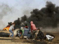 Palestinian protesters cover during clashes with Israeli troops along Gaza's border with Israel, east of Khan Younis, Gaza Strip, Thursday, April 5, 2018. An Israeli airstrike in northern Gaza early on Thursday killed a Palestinian, while a second man died from wounds sustained in last week's mass protest. The fatalities bring to 21 the number of people killed in confrontations in the volatile area over the past week with a new round of protests along the border is expected on Friday. (AP Photo/Adel Hana)