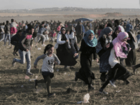 Palestinian protesters run for cover from teargas fired by Israeli soldiers during clashes with Israeli troops along the Gaza Strip border with Israel, east of Beit Lahiya, Gaza Strip, Saturday, March 31, 2018. (AP Photo/Adel Hana)