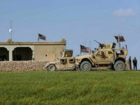 In this picture taken Thursday, March 29, 2018, U.S. soldiers, left, sit on a house that turned to an outpost on a road leading to the tense front line between U.S-backed Syrian Manbij Military Council fighters and Turkish-backed fighters, at Halawanji village, north of Manbij town, Syria. The front line has grown more tense in recent days as Turkey threatens to advance on the town to clear it of the U.S-backed fighters. U.S troops have increased their patrols in the area, local commanders say, to prevent an outbreak of fighting and to prevent Turkey from advancing on Manbij. (AP Photo/Hussein Malla)