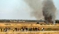 Palestinians demonstrate along Gaza's border with Israel as smoke rises from a field set on fire by a molotov cocktail delivered by kite from the coastal territory
