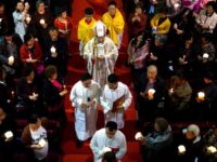 In this Saturday, March 31, 2018, file photo, Chinese Bishop Joseph Li Shan, center, walks down the aisle during a Holy Saturday Mass on the evening before Easter at the Cathedral of the Immaculate Conception, a government-sanctioned Catholic church in Beijing. China says restricting the Vatican’s control over the appointment of bishops does not infringe upon Chinese believers’ religious freedom. The remark during a State Council briefing comes as Beijing and the Holy See are negotiating an historic agreement over the method of selecting bishops in China. (AP Photo/Mark Schiefelbein, File)