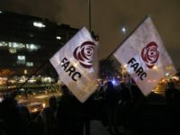 Supporters of former FARC rebel Jesus Santrich hold flags of his political party to protest his arrest outside the Attorney General Office where he is being held in Bogota, Colombia, Monday, April, 9, 2018. Seuxis Hernandez, a blind rebel ideologue best known by his alias Jesus Santrich, was picked up Monday at his residence in Bogota on charges that he conspired with three others to smuggle several tons of cocaine into the U.S. with a wholesale value of $15 million. (AP Photo/Fernando Vergara)