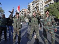 Syrian soldiers hold their weapons as they dance and chant slogans against U.S. President Trump during demonstrations following a wave of U.S., British and French military strikes to punish President Bashar Assad for suspected chemical attack against civilians, in Damascus, Syria, Saturday, April 14, 2018. Hundreds of Syrians are demonstrating in a landmark square in the Syrian capital, waving victory signs and honking their car horns in a show of defiance. (AP Photo/Hassan Ammar)