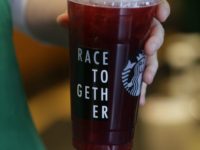 In this March 18, 2015, file photo, a Starbucks barista holds an iced tea drink with a "Race Together" sticker on it at a Starbucks store in Seattle. Three years ago, Starbucks was widely ridiculed for trying to start a national conversation on race relations by asking its employees to write the words “Race Together” on coffee cups. The initiative, though it backfired, was in line with the company’s longstanding effort to project a progressive and inclusive image. The company is now through the looking glass, trying to tamp down a racially charged uproar over the arrest of two black men at one of its stores in Philadelphia. (AP Photo/Ted S. Warren, File)