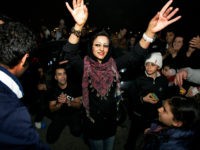 Between the people, a woman dances, in the Pardisan Park in Tehran, Iran, Tuesday, March 13, 2012, during Chaharshanbe Souri, or Wednesday Feast, an ancient Festival of Fire, on the eve of the last Wednesday of the year. Iranians jump over burning bonfires while throwing firecrackers, celebrate arrival of the spring which coincides with Iranian new year, or Nowruz. Setting off firecrackers has turned into careless massive explosions in the recent years, which leaves many wounded every year, prompting strong reactions by police. The festival, came from pre-Islamic Zoroastrianism era, has been discouraged by conservative Islamist rulers after 1979 Islamic Revolution, but without any success. (AP Photo/Vahid Salemi)