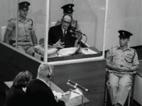 Nazi war criminal Adolph Eichmann stands in a protective glass booth flanked by Israeli police during his trial June 22, 1961 in Jerusalem. The Israeli police donated Eichmann's original handprints, fingerprints and mugshot to Jerusalem's Yad Vashem Holocaust memorial ahead of Israel's annual Holocaust remembrance day May 4, 2005 which this year also marks the 60th anniversary of the Nazi's World War II defeat in 1945. (Photo by GPO via Getty Images)