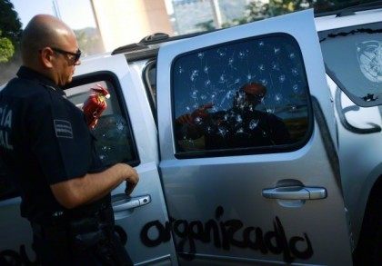 A federal police officer holds a fire extinguisher as he stands next to the vandalized vehicle of Acapulco's Mayor Luis Walton Aburto after a demonstration demanding justice for the 43 missing students from Ayotzinapa Teacher Training College, in Aca