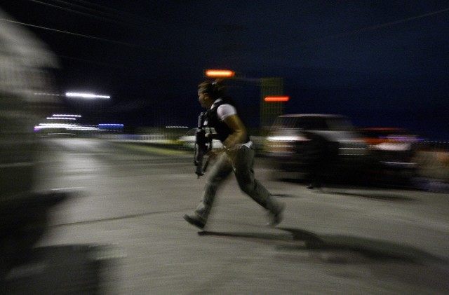 Police detective runs for cover during a police operation to regain control of a jail in Ciudad Juarez