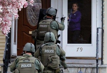 File photo of a member of the SWAT team motioning to a resident to come out of the house as they conduct a house to house search for Dzhokar Tsarnaev, the one remaining suspect in the Boston Marathon bombing, in Watertown