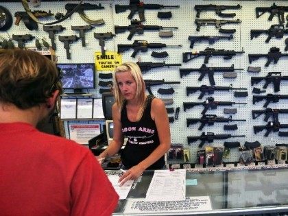 In this July 20, 2014 photo, with guns displayed for sale behind her, a gun store employee