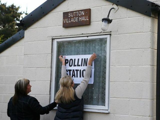 Electoral workers put up a sign in the window of a building being used as a polling statio