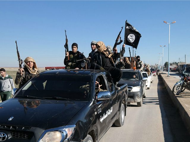 In this photo released on May 4, 2015, by a militant website, which has been verified and is consistent with other AP reporting, Islamic State militants pass by a convoy in Tel Abyad town, northeast Syria. In contrast to the failures of the Iraqi army, in Syria Kurdish fighters are …