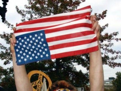 A masked antiwar protester holds a U.S. flag upside down in protest of the war in Iraq Oct