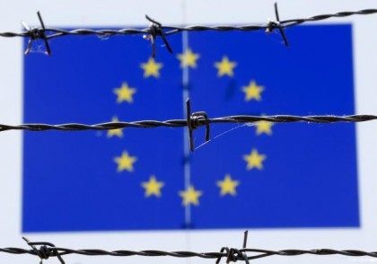 A barbed wire is seen in front of a European Union flag at an immigration reception centre in Bicske