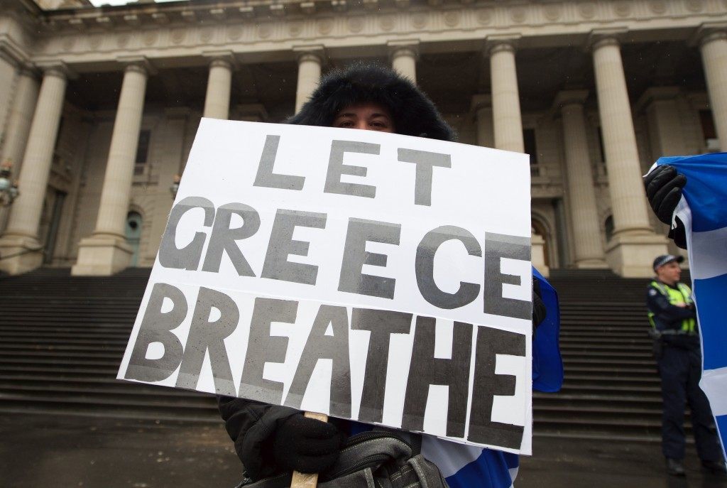 A protestor holds a banner at a Greece solidarity rally outside Parliament House in Melbourne, Australia. THEO KARANIKOS/AFP/Getty Images