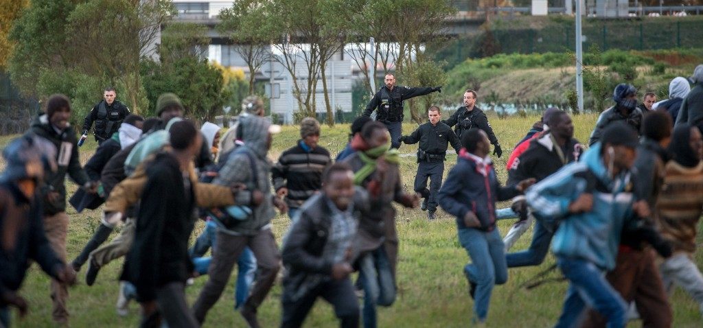 Policemen try to prevent migrants from reaching the Channel Tunnel (PHILIPPE HUGUEN/AFP/Getty Images)