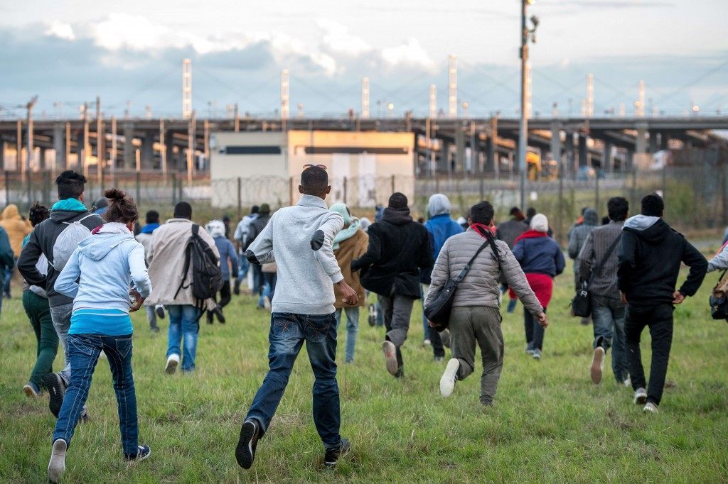 Migrants who managed to pass the police block on the Eurotunnel site run towards the boarding docks (PHILIPPE HUGUEN/AFP/Getty Images)