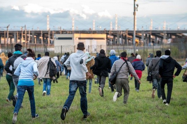 Migrants who managed to pass the police block on the Eurotunnel site run towards the board