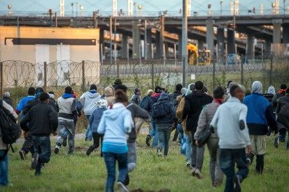 Migrants who managed to pass the police block on the Eurotunnel site run towards the board