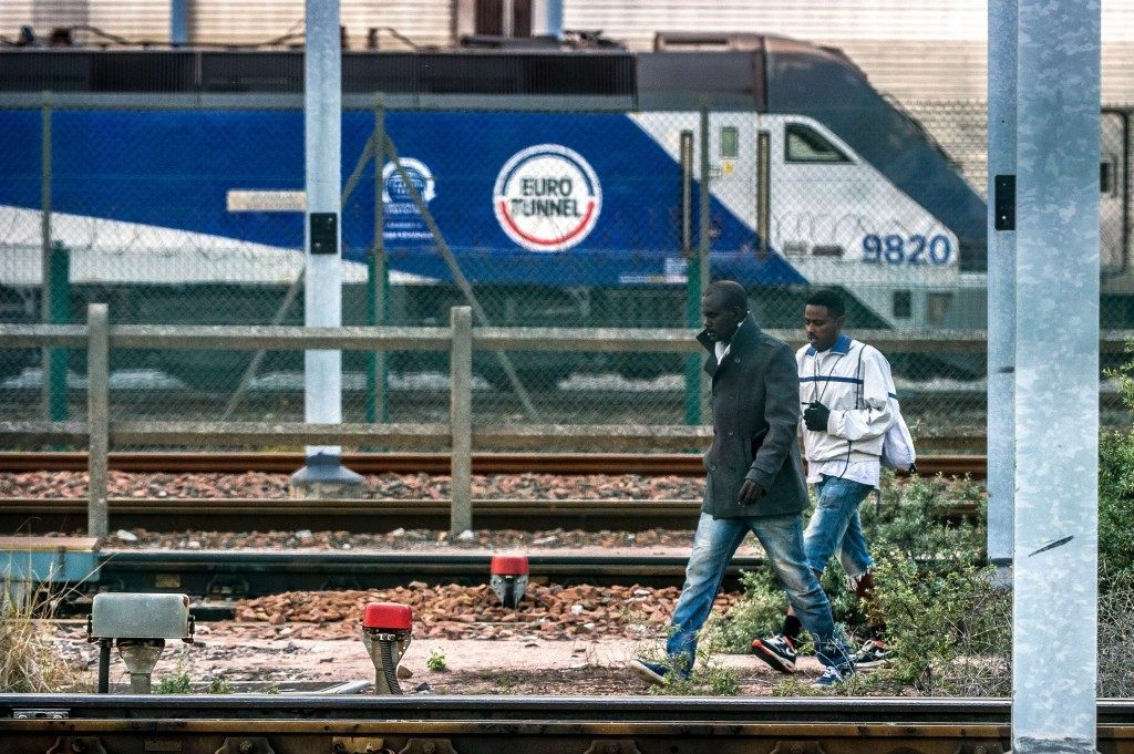 Migrants walk on the tracks in the Eurotunnel site (PHILIPPE HUGUEN/AFP/Getty Images)