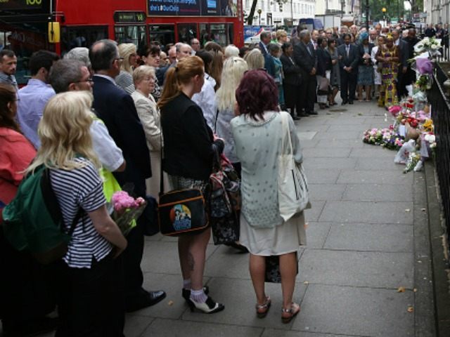 Buses pass by as family members attend a remembrance ceremony at the spot where 13 people