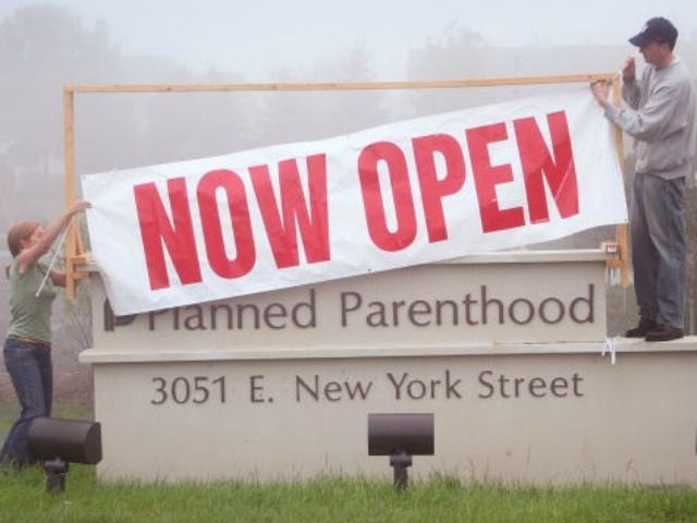 Workers at a Planned Parenthood clinic hang a banner to announce the opening of the facili