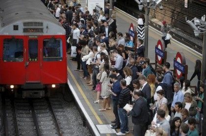 Commuters at Earls Court underground station, awaiting the arrival of a train, attempt to complete their journey on Wednesday evening, in London