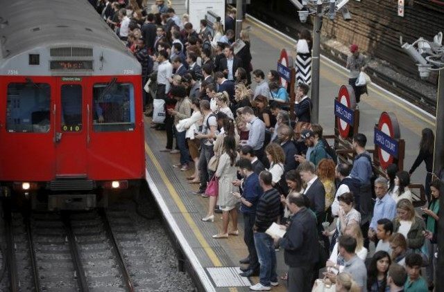 Commuters at Earls Court underground station, awaiting the arrival of a train, attempt to
