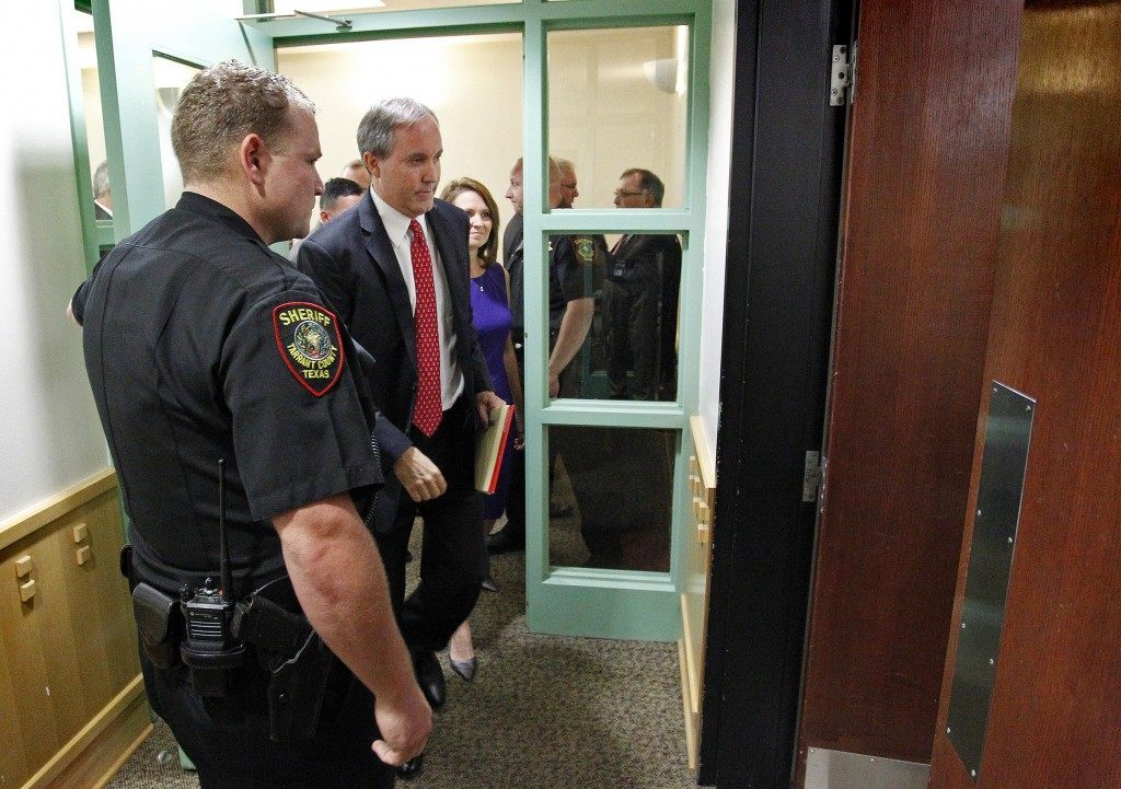 Texas Attorney General Ken Paxton, second left,  leaves court after a hearing on Paxton's felony securities indictment, Thursday, Aug. 27, 2015, at the Tarrant County Courthouse in Fort Worth, Texas. Paxton pleaded not guilty Thursday to charges alleging that he defrauded investors before he became the state's top lawyer, and his attorney Joe Kendall announced that he would no longer represent him.  (Star-Telegram/Rodger Mallison via AP, Pool)