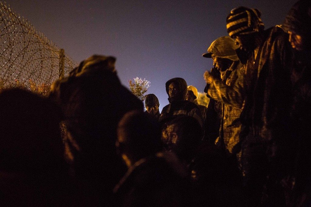 Men gather beside a security fence beside train tracks near the Eurotunnel terminal in Coquelles in the early morning hours on August 1, 2015 (Rob Stothard/Getty Images)