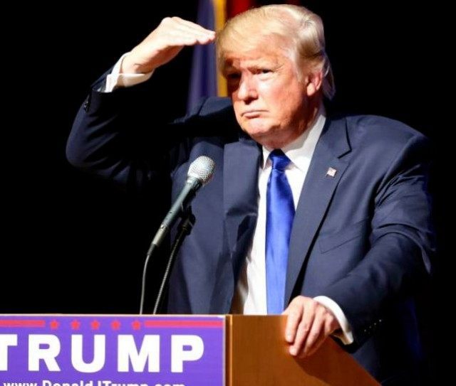 Republican presidential candidate Donald Trump shields his eyes from the lights as he take