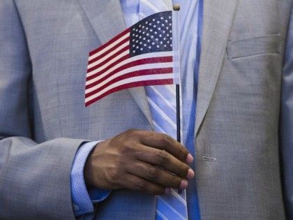 A man holds an US flag prior to taking the citizenship oath to become a US citizen during