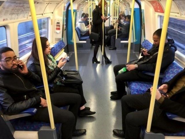 Commuters use their mobile devices on an underground tube train in London