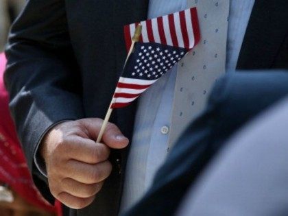 A man holds an American Flag before taking the Oath of Allegiance during a special naturalization ceremony at the Metropolitan Museum of Art on July 22, 2014 in New York City. Over fifty people representing countries from Albania to Burundi took part in the morning ceremony at the American Wing …