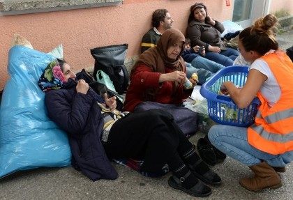 A helper gives food to migrants waiting for a special &hellip;