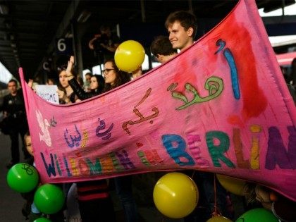 SCHOENEFELD, GERMANY - SEPTEMBER 13: People hold a banner to welcome migrants arriving on an ICE high-speed train of Deutsche Bahn from Munich near Berlin on September 13, 2015 in Schoenefeld, Germany.