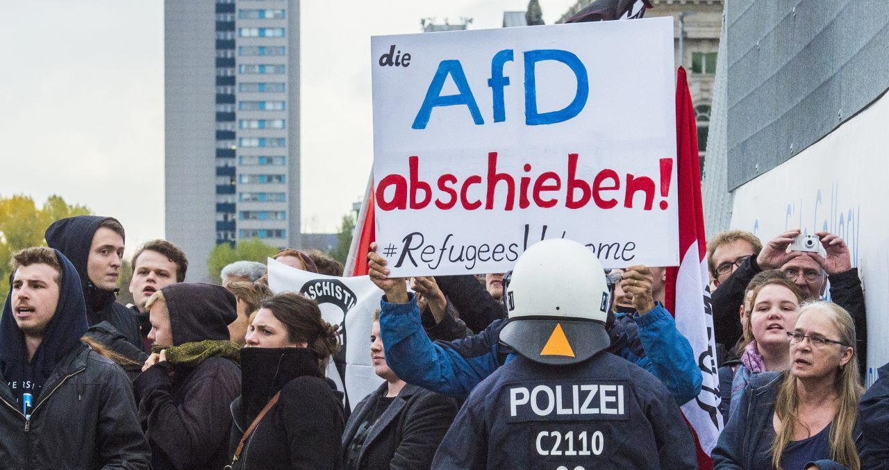 Counter-demonstrators hold a placard telling the AfD to "Get lost" and declare "refugees welcome" (JOHN MACDOUGALL/AFP/Getty Images)