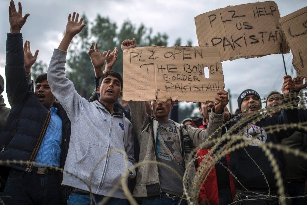 Migrants and refugees from Pakistan demonstrate behind razor wire in front of Macedonian police as they wait to cross the Greek-Macedonian border near Gevgelija on November 22, 2015. Serbia and Macedonia, which lie on the main migrant route to northern Europe, have begun restricting the entry of refugees to just those from certain countries, the UN refugee agency said on November 19. AFP PHOTO / ROBERT ATANASOVSKI / AFP / ROBERT ATANASOVSKI (Photo credit should read ROBERT ATANASOVSKI/AFP/Getty Images)